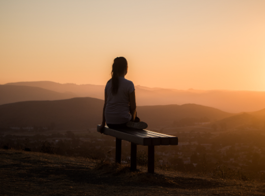 Woman sat on bench on top of mountain
