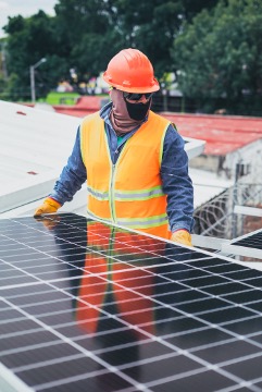 Person working on a solar panel wearing high visibility uniform.